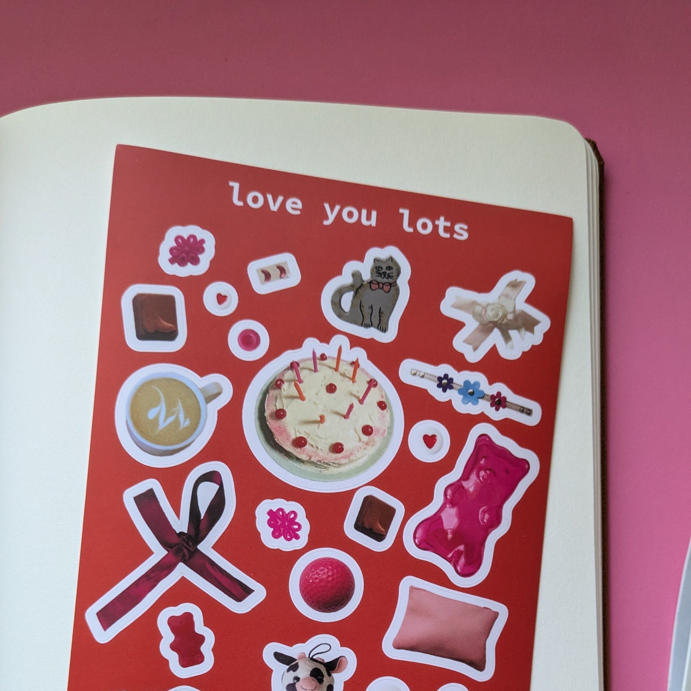 A sticker sheet with various designs including a teddy bear, hearts, and other romantic-themed elements, with a red background and the text 'love you lots'.