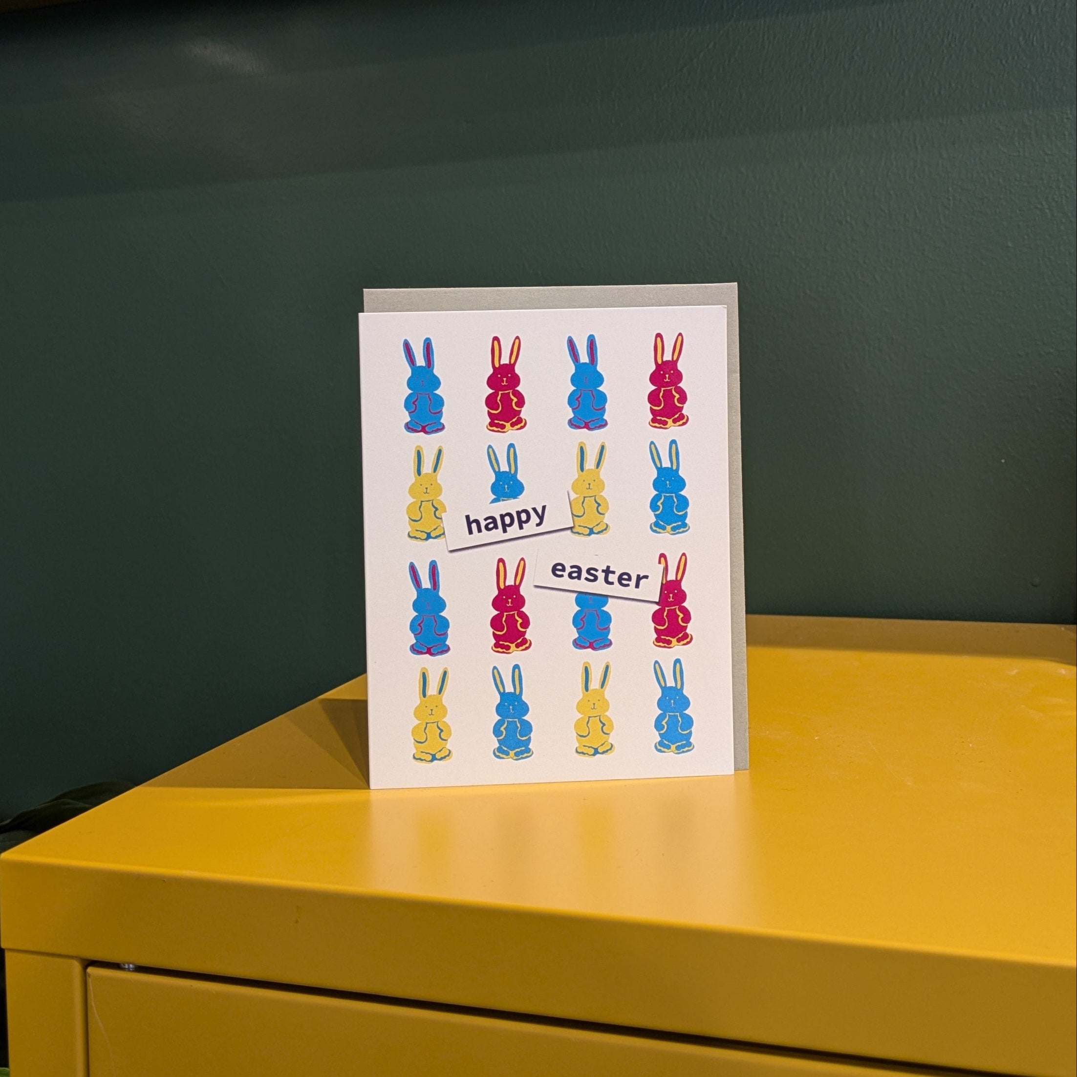 Colorful Easter card on a yellow surface with a green wall in the background