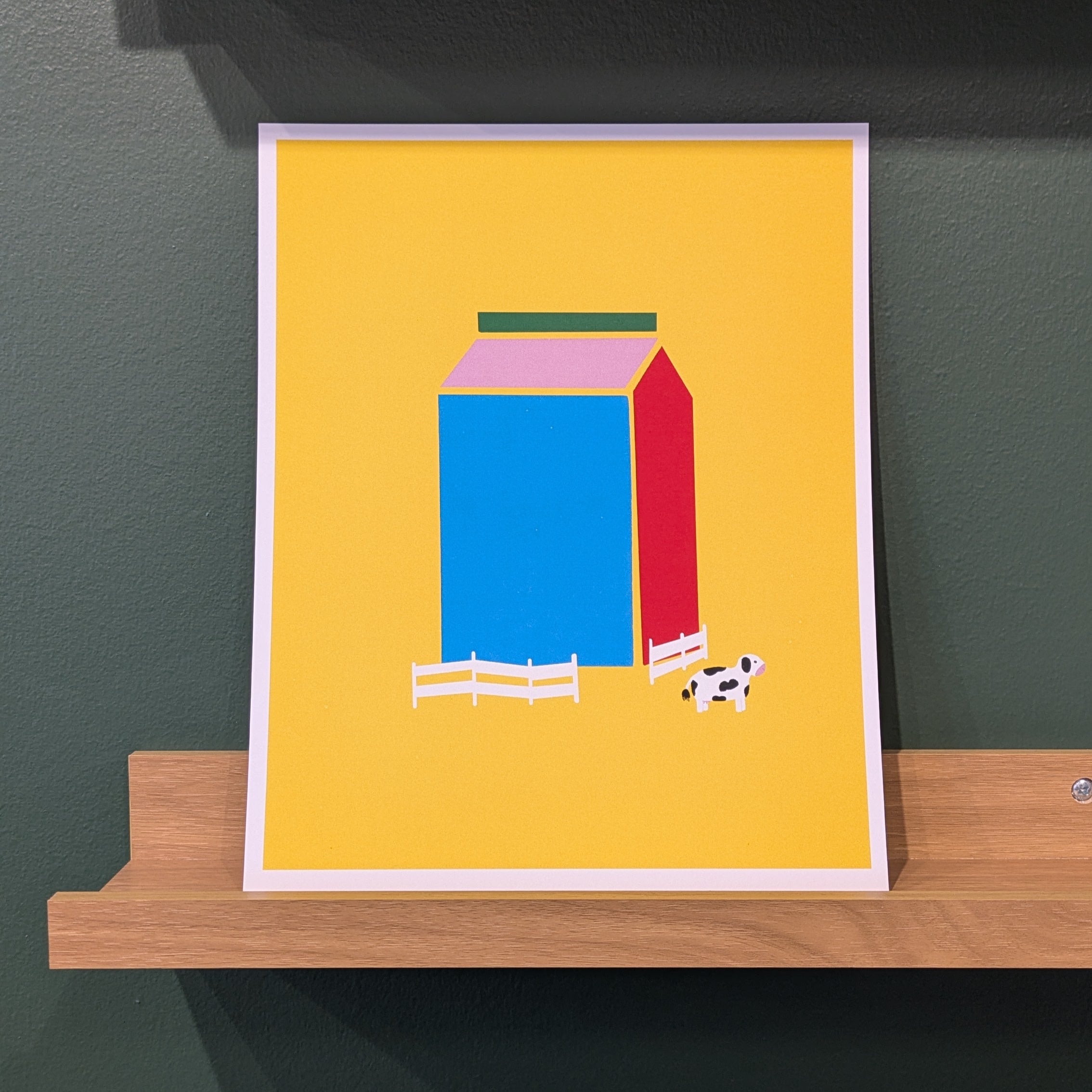 Framed artwork of a colorful abstract design on a dark wall with a wooden shelf.