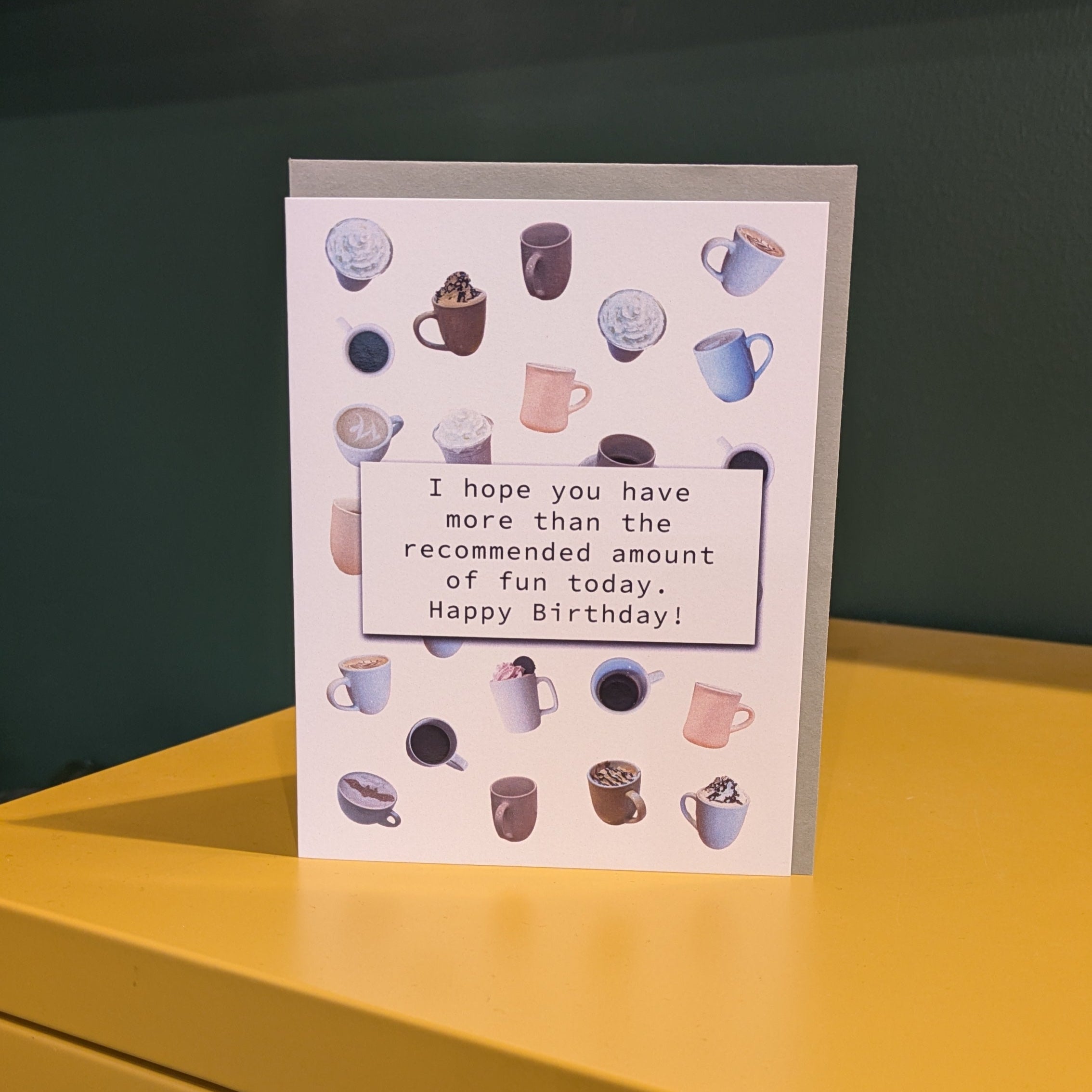 Greeting card with coffee-themed design on a yellow surface with a dark background