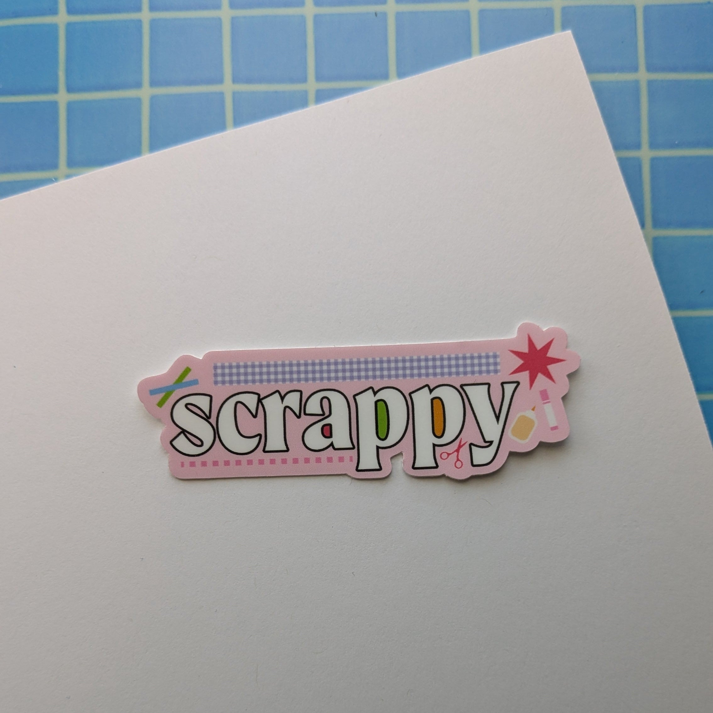 Decorative paper with 'scrapy' text on a blue grid background